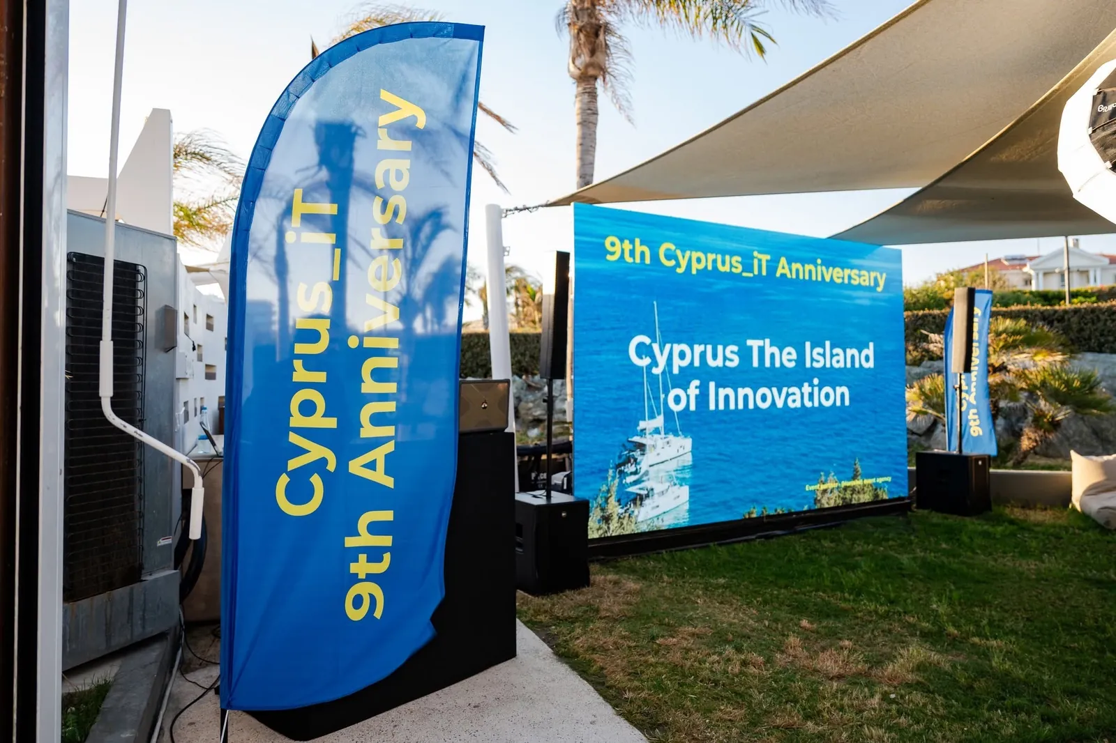 Cyprus_iT ninth anniversary flag beside a screen reading Cyprus — The Island of Innovation